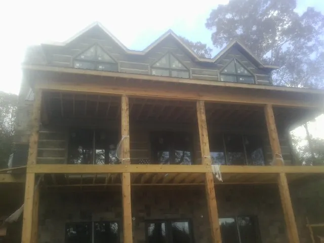 Dormers and porch framing on a large log home under construction — Roof Coating work by our crew in Smithfield