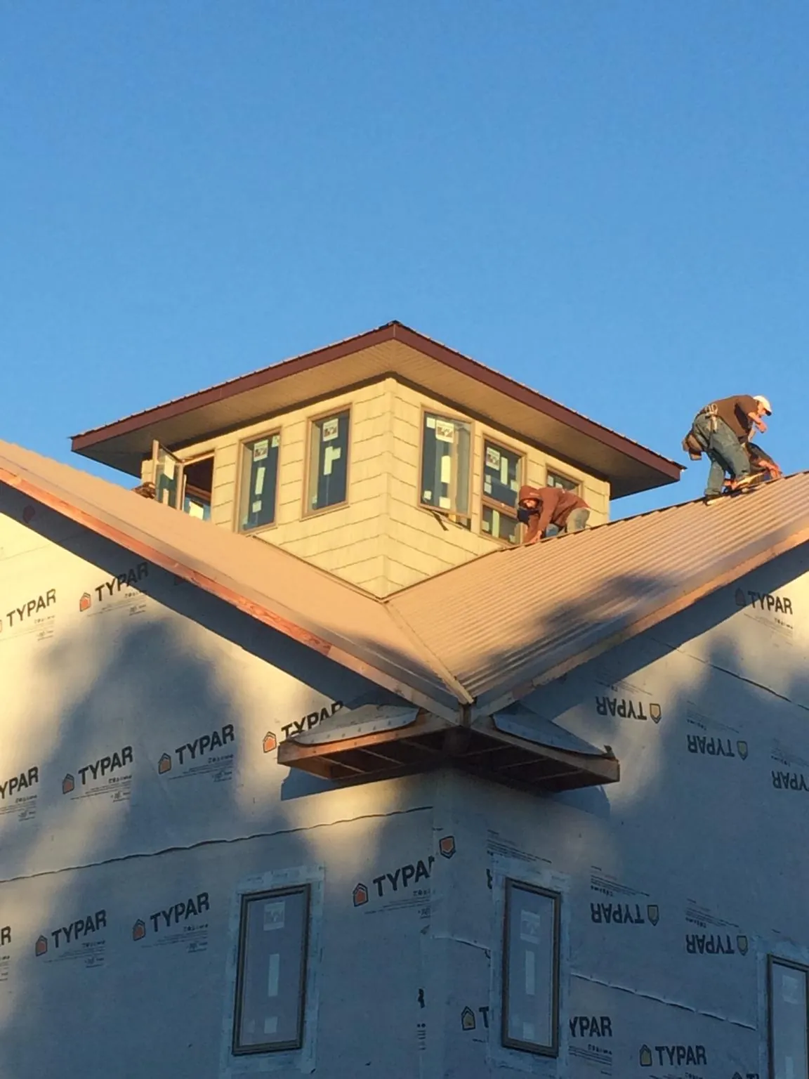 Roofers working around a rooftop cupola on a new metal roof at sunset — Roof Waterproofing in Smithfield by Roofing Brothers